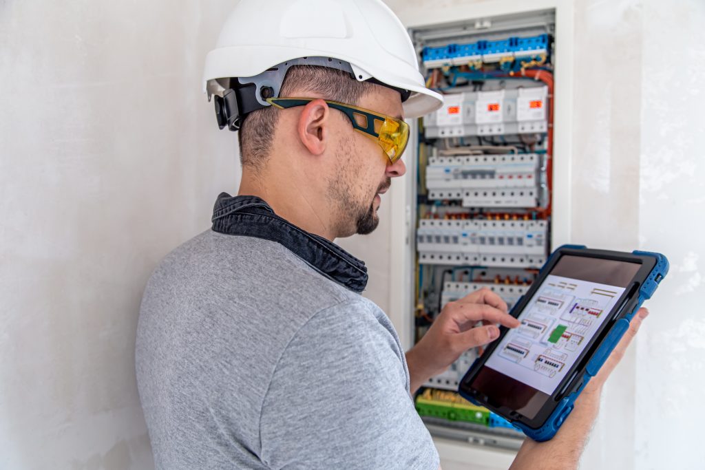 electrical technician looking focused while working in a switchboard with fuses.