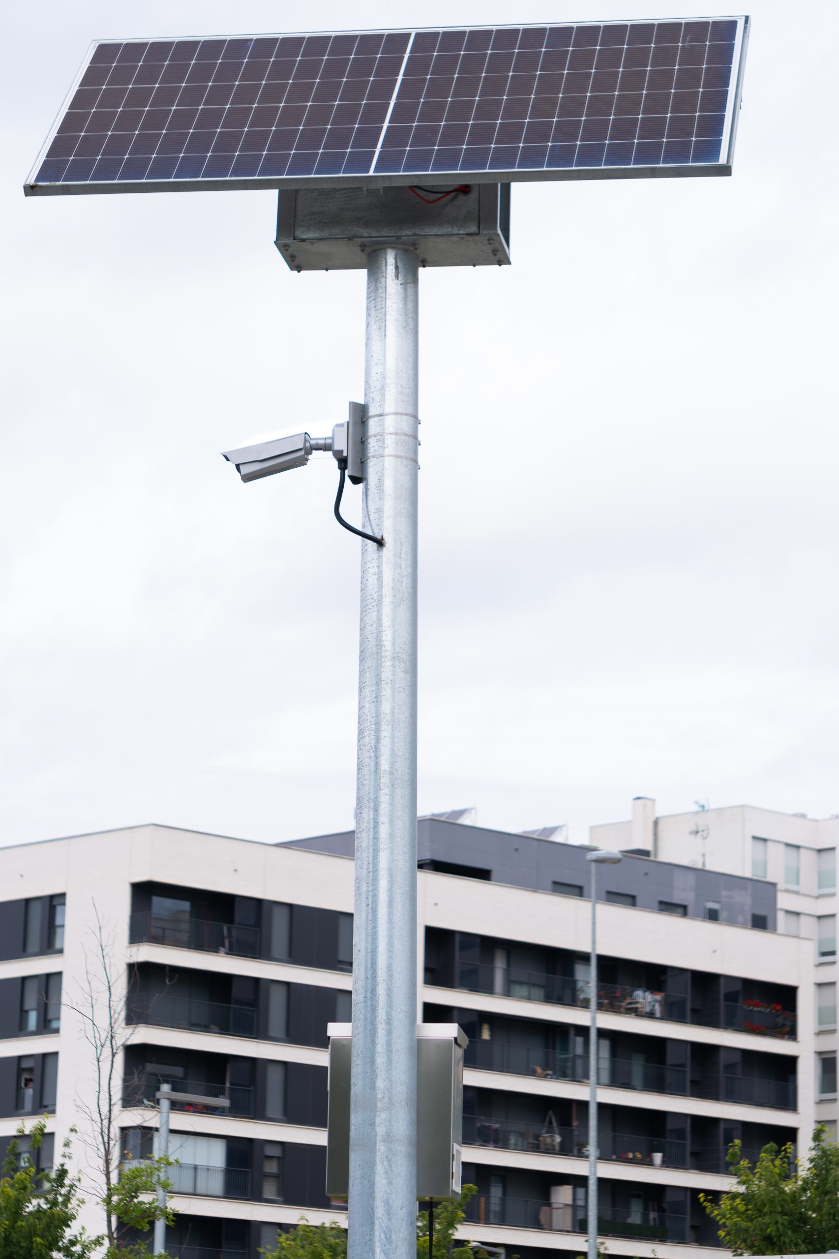 solar powered video surveillance systems. security and burglary protection systems. security video surveillance camera installed on a pole next to a residential building. digital technology.
